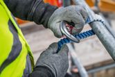 安全装備を身に着けた人が、足場にクライミング用ランヤードを固定する。