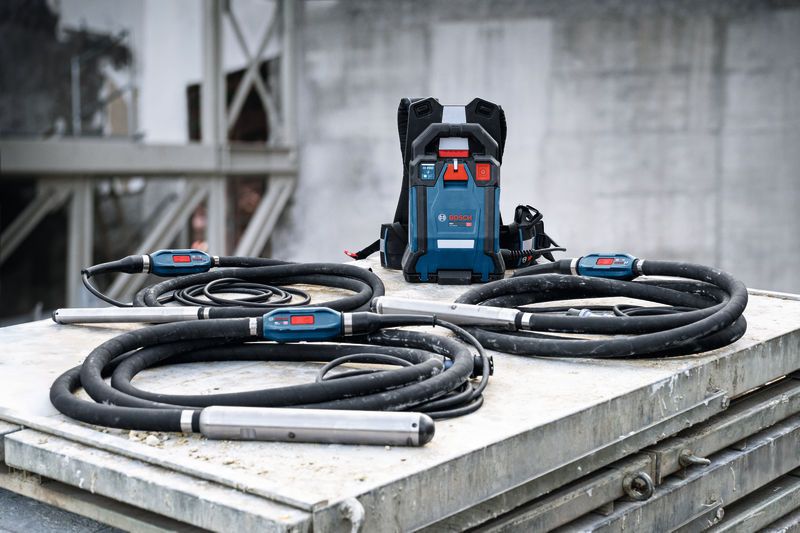 長い黒いホースと制御ユニットを備えたコンクリート振動工具が金属表面上に設置されています。