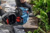 安全装備を身に着けた人が、庭石に電動工具を操作している。