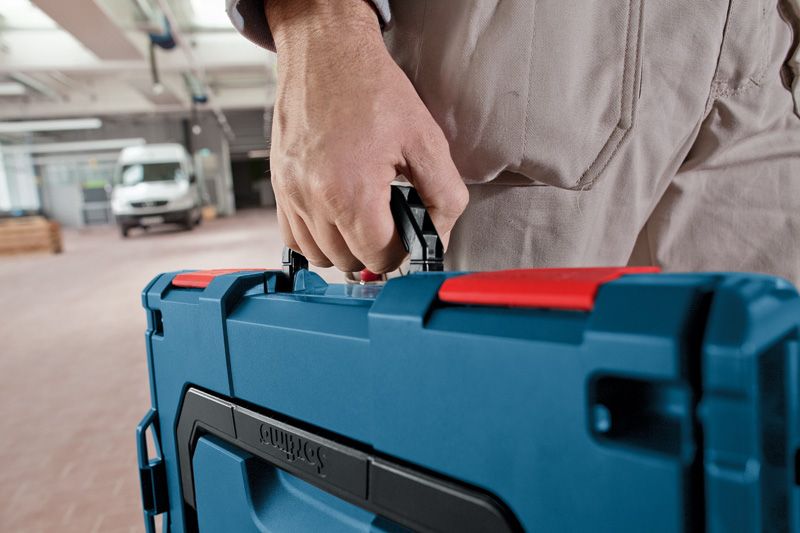 作業場で青い工具ケースを運んでいる人。.