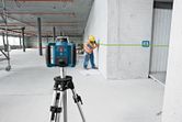 安全装備を身に着けた人が、緑色のレーザー測量器を使って壁に印をつけている。